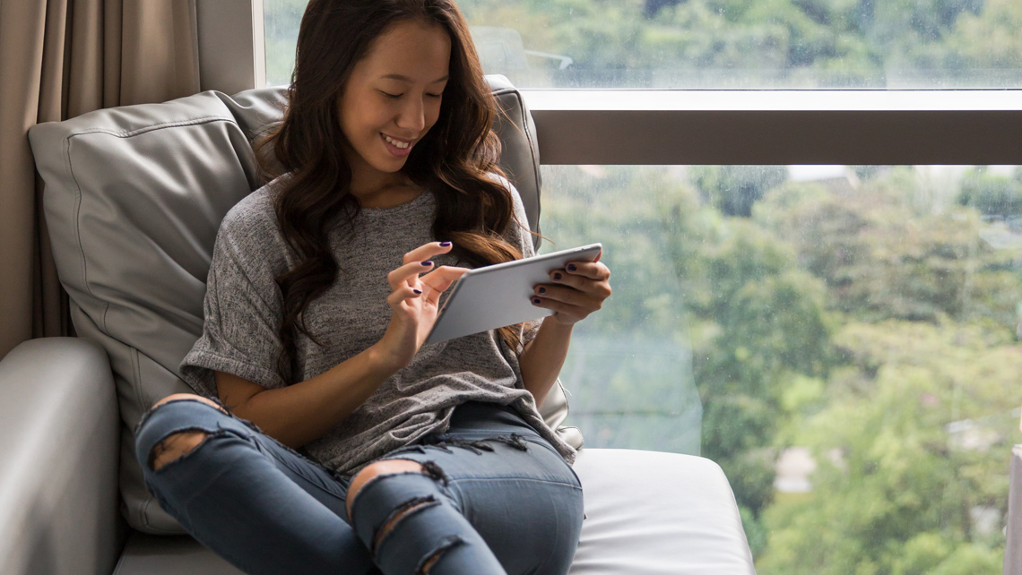 A person browsing a tablet at livingroom couch.