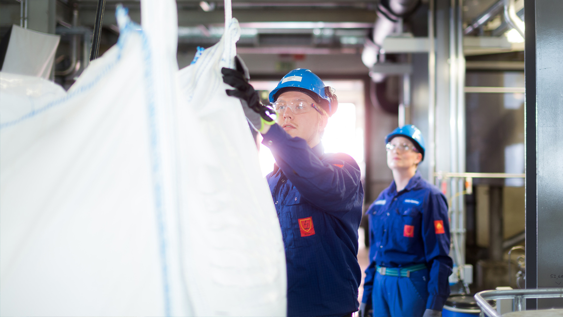 Two persons working in a chemical factory.