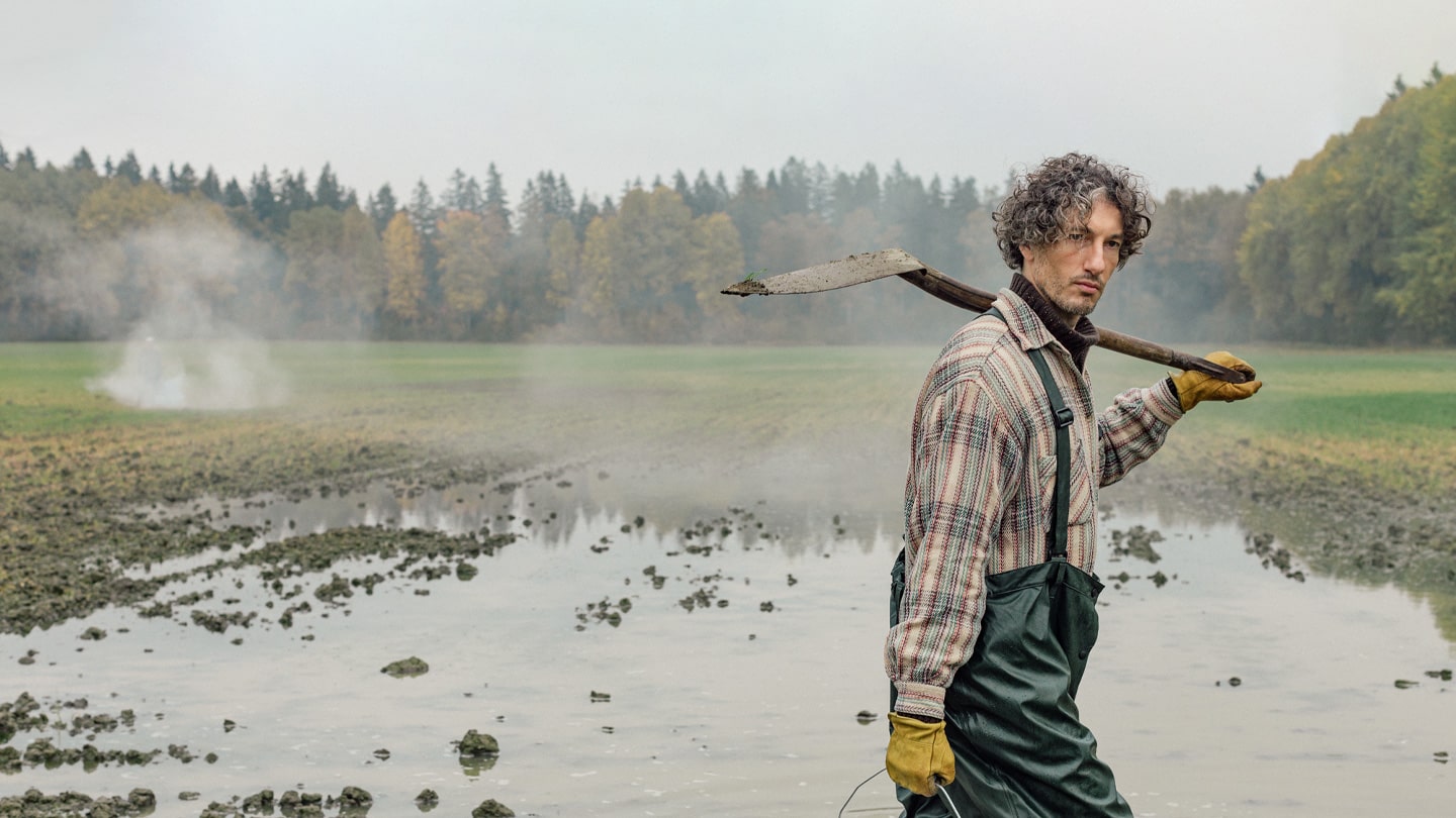 A farmer holding a shovel in a field.