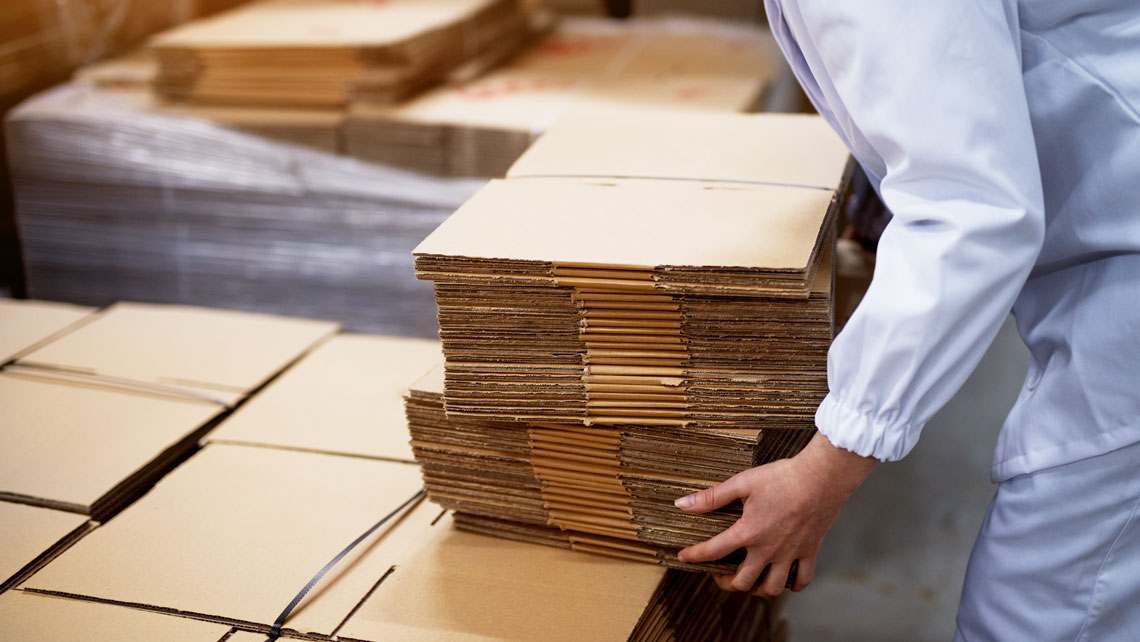 person stacking flat corrugated boxes at a warehouse